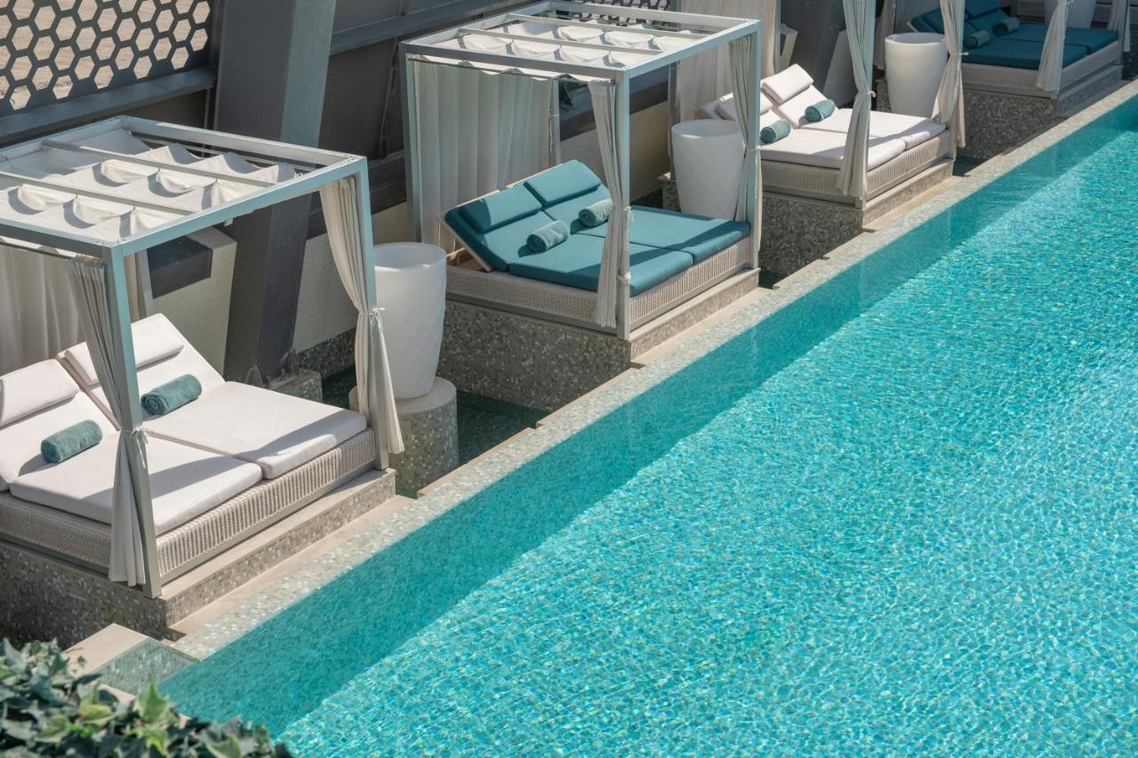 Steigenberger Hotel Доха Екстер'єр фото The photo shows a luxurious pool area with several stylish cabanas placed alongside a clear, blue swimming pool. Each cabana features comfortable lounge chairs with cushions, and there are white planters nearby. The overall design conveys a serene an