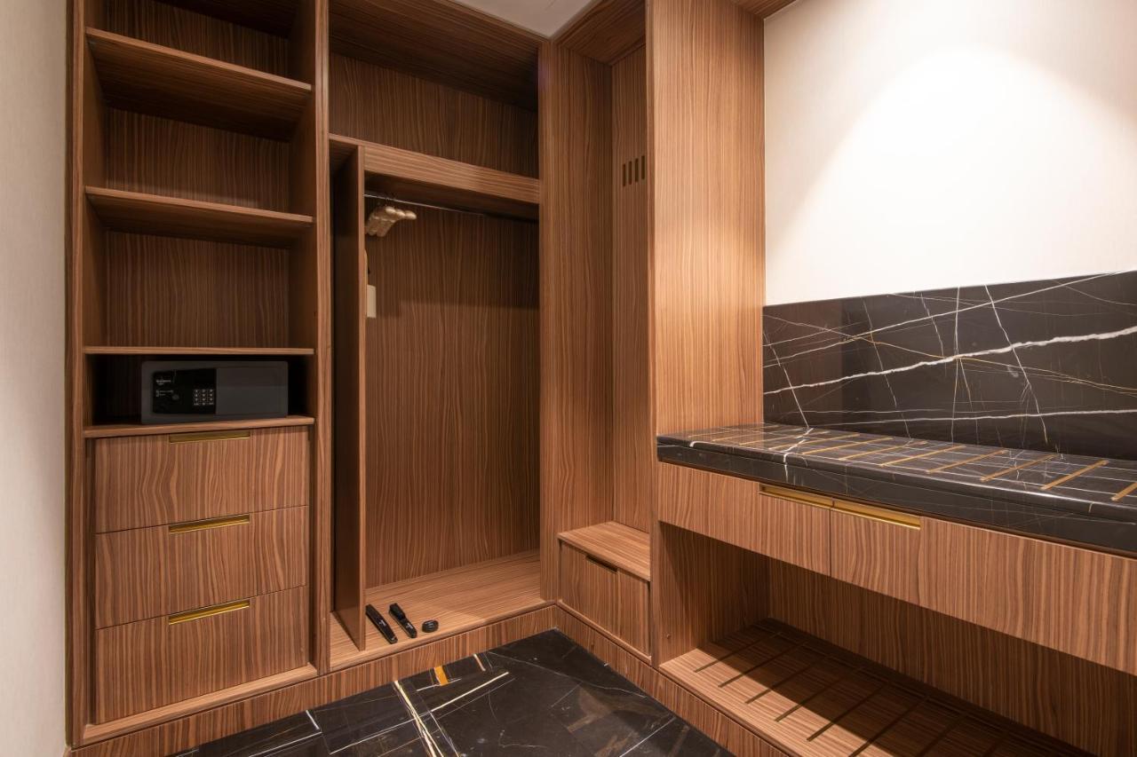 Steigenberger Hotel Доха Екстер'єр фото The photo shows a stylishly designed closet or wardrobe area. It features wooden panels with a warm finish. On the left side, there are open shelves, as well as a section for hanging clothes. Below, there are two drawers, adding extra storage space. 