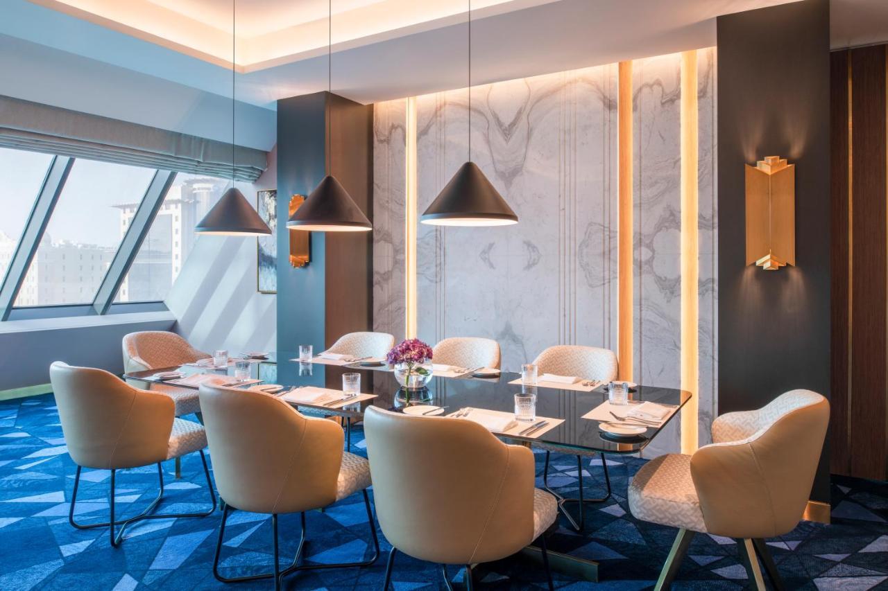 Steigenberger Hotel Доха Екстер'єр фото The photo showcases a stylish meeting room. It features a modern, elegant design with a large rectangular table surrounded by plush chairs. The room has a contemporary color palette, primarily using soft beige and rich blue tones. Large windows allow