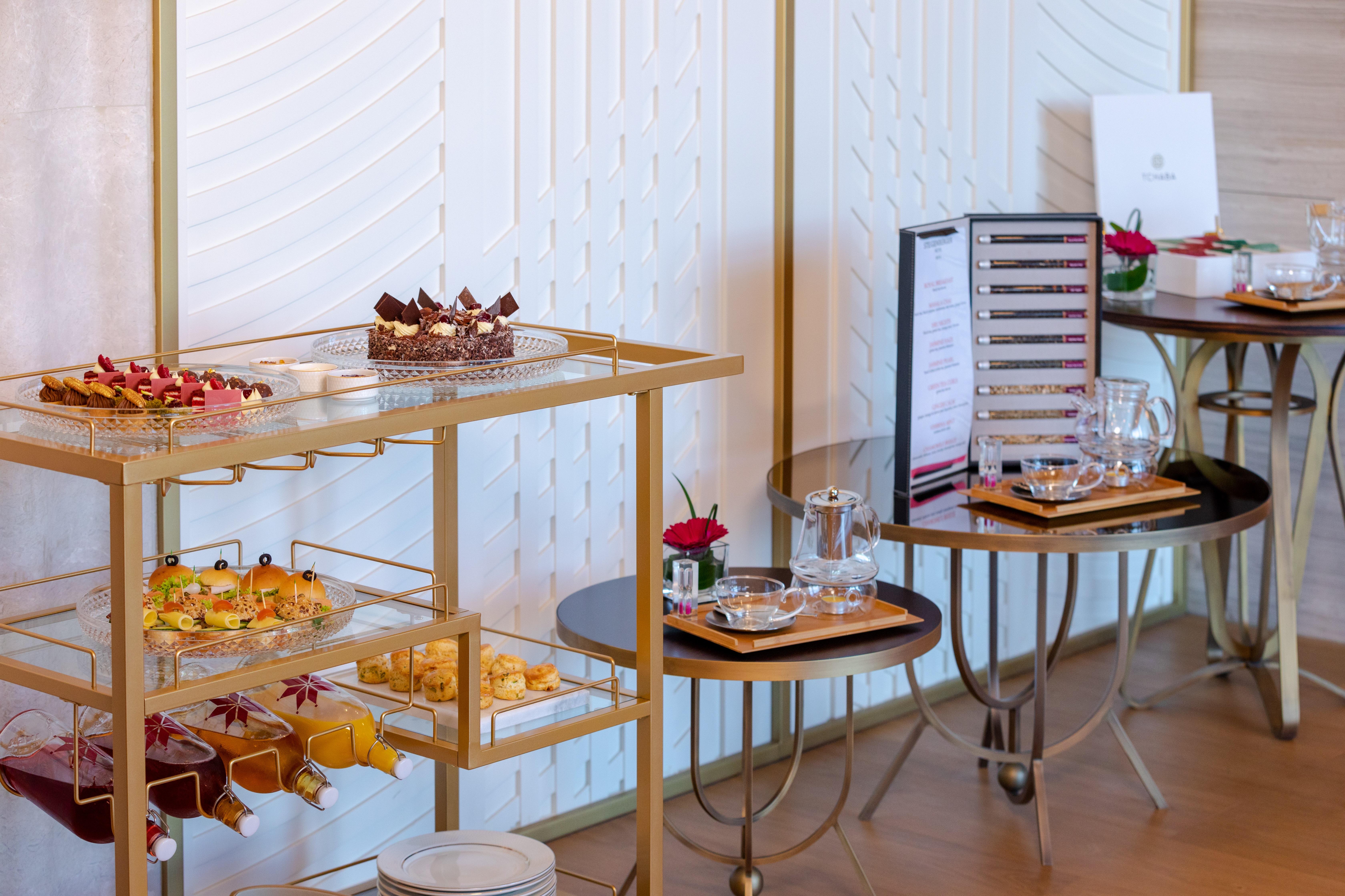 Steigenberger Hotel Доха Екстер'єр фото The photo shows a beautifully arranged buffet table featuring a variety of desserts and snacks. There is a gold cart displaying an assortment of pastries and small treats, including colorful hors d'oeuvres and mini desserts, likely for a high-end eve