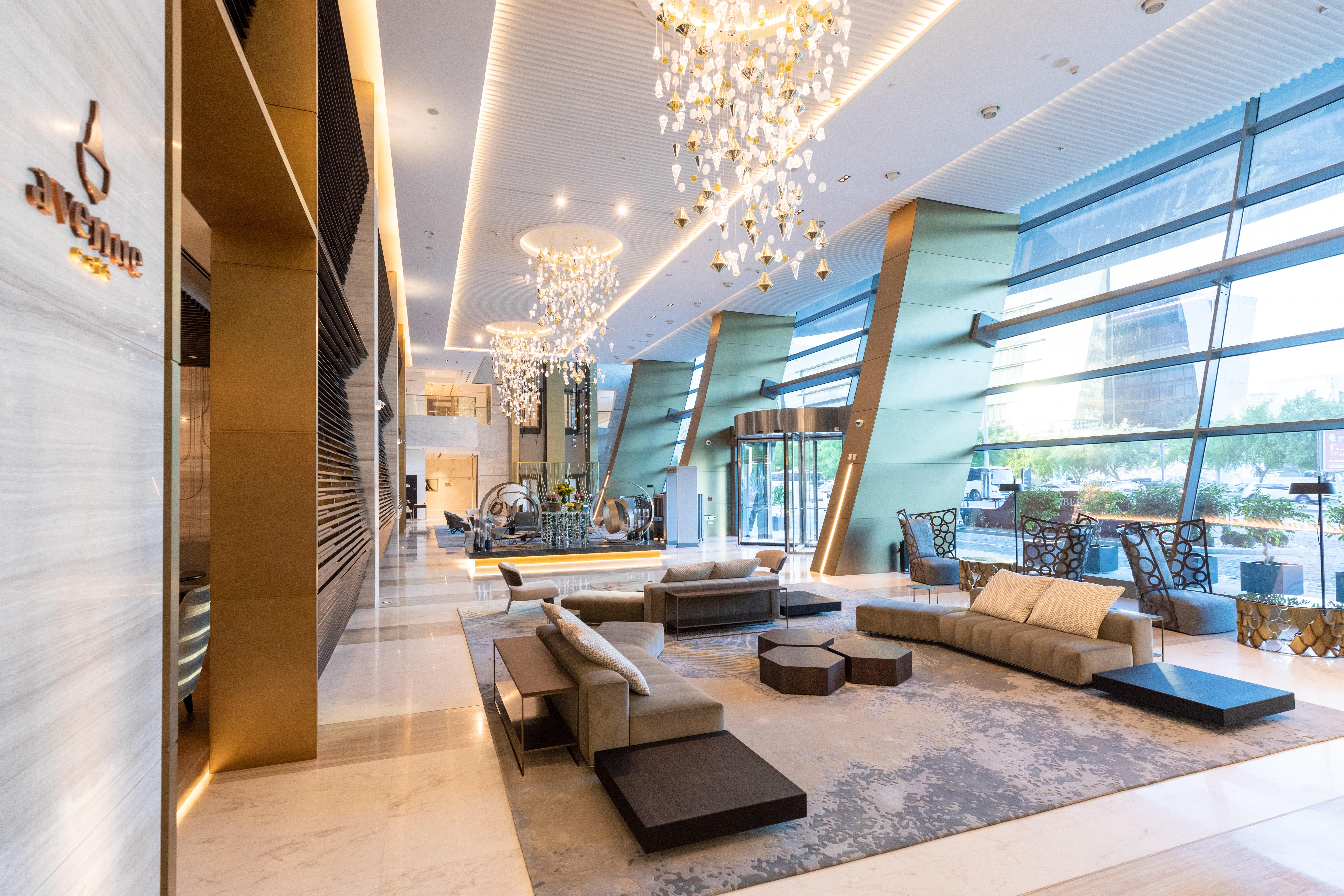 Steigenberger Hotel Доха Екстер'єр фото The photo shows a modern and elegant hotel lobby. It features stylish furniture, including sofas and coffee tables, arranged in a welcoming layout. The space is well-lit by several large chandeliers hanging from the ceiling, adding a touch of luxury.