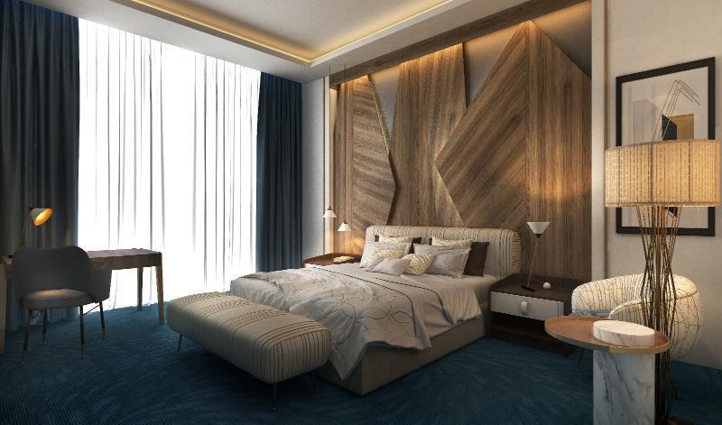 Steigenberger Hotel Доха Екстер'єр фото The photo shows a modern bedroom with a stylish and contemporary design. The room features a large bed with a textured headboard, complemented by plush bedding. There are two bedside lamps on either side of the bed, and a small seating area with an u